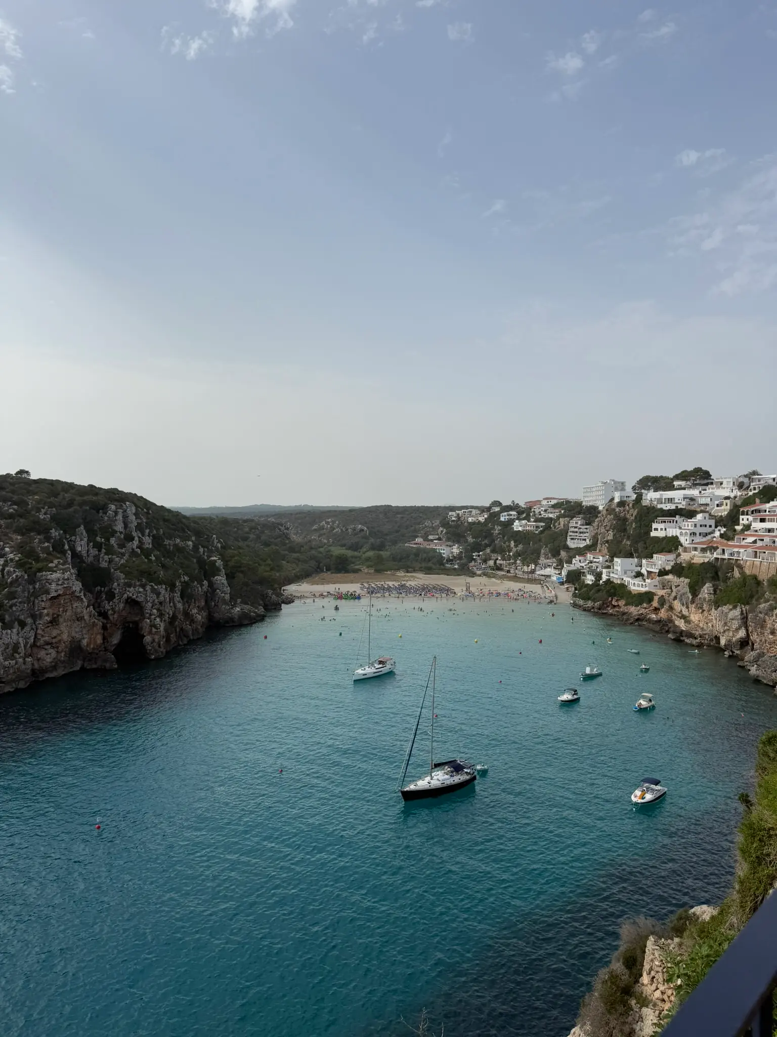 Vue aérienne d'une crique de Minorque avec un petit village blanc au bord de l'eau